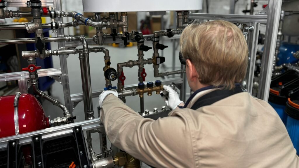 Engineer working on industrial pipe system in a factory for heating and production adjustment.